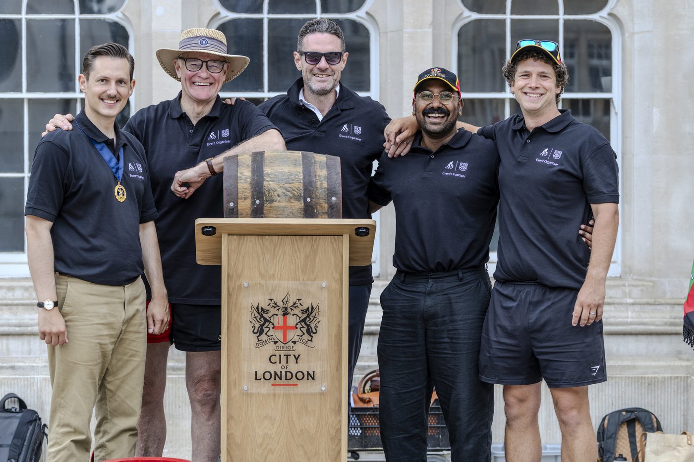 Five of the organising team in Event Organiser shirts, beside a cask at the City of London lectern